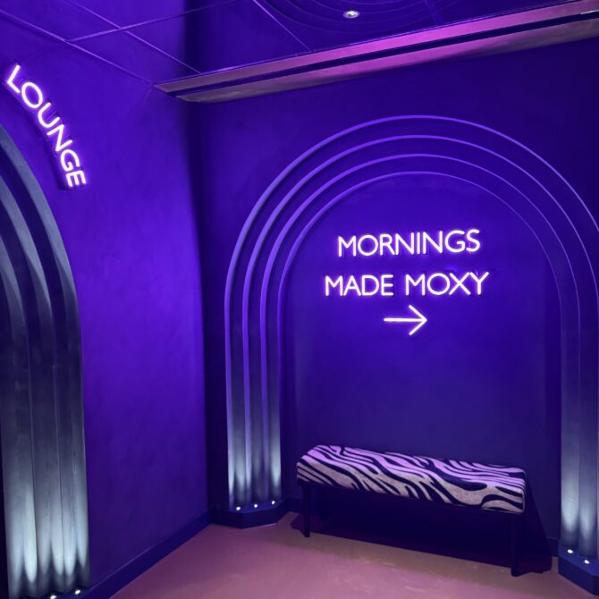 Purple-lit Moxy signage and ceiling detail