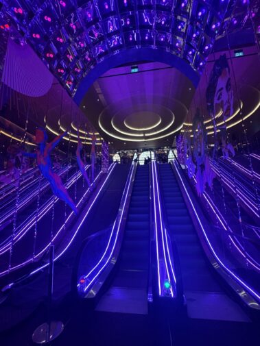 Purple-lit escalators and circular ceiling lighting at Moxy London Piccadilly Circus